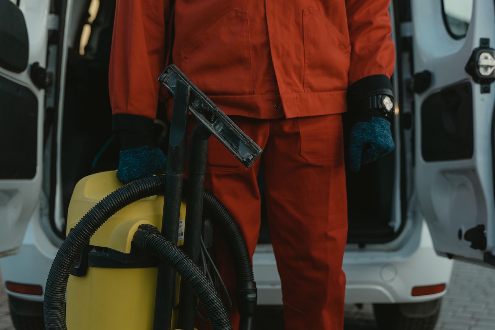Technician steam cleaning car carpet during an interior detail